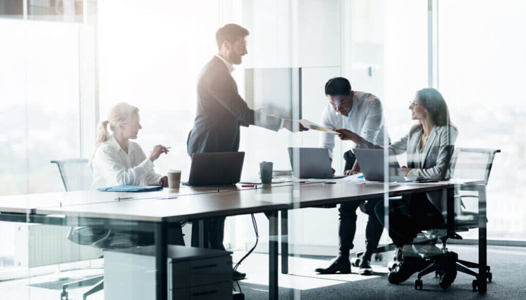 People standing near table, team of young businessmen working and communicating together in office