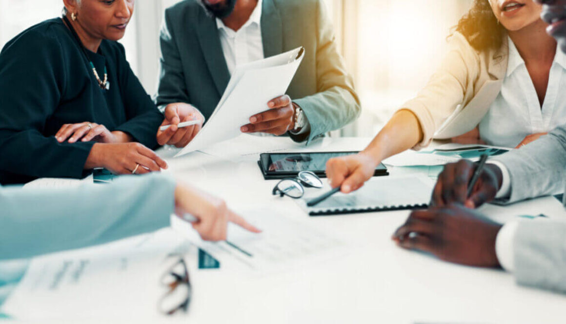 Business people, paperwork and hands with discussion in meeting for finance forecasting, data analysis or planning. Financial analyst, teamwork or pointing to revenue statement for capital allocation