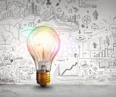 Glass glowing light bulb and business sketched ideas