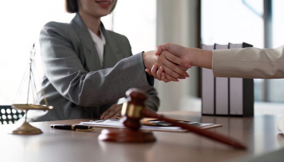 Professional Lawyer Handshake in Office Setting with Legal Documents and Scales of Justice
