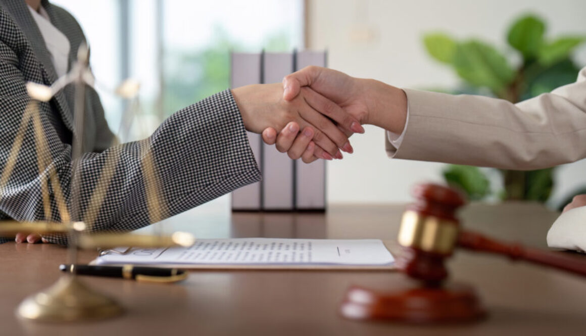 Professional Lawyer Handshake in Office with Legal Documents, Scales of Justice, and Gavel on Desk