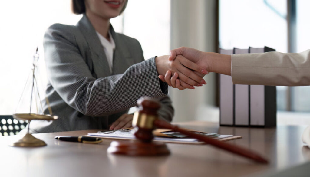 Professional Lawyer Handshake in Office Setting with Legal Documents and Scales of Justice